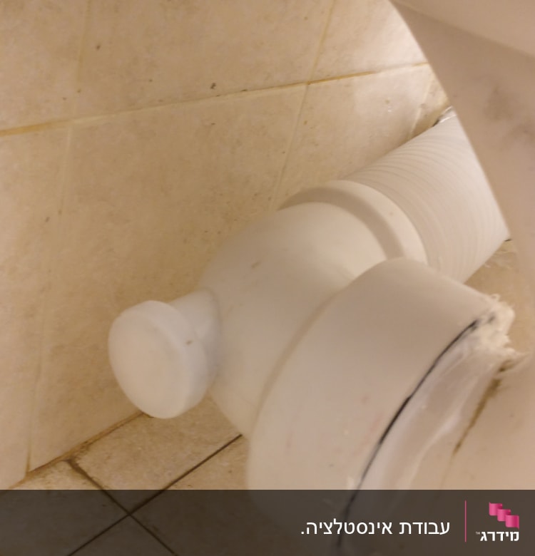 צינור ביוב לבן מחובר לקיר קרמיקה
